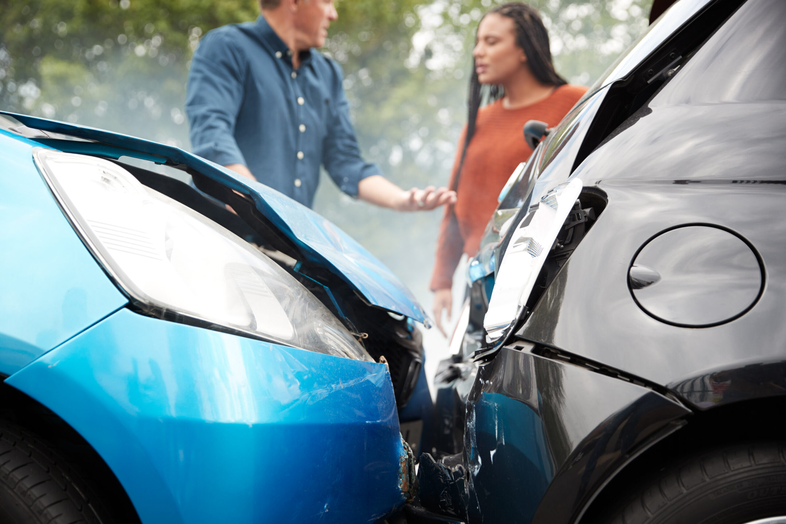 woman and man stand behind wrecked cars- olathe car accident attorney