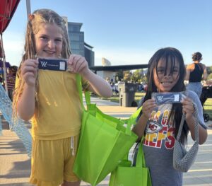 two girls stand holding up an InJerry Kit- Wallentine Injury Law 2025 Community Involvement Report