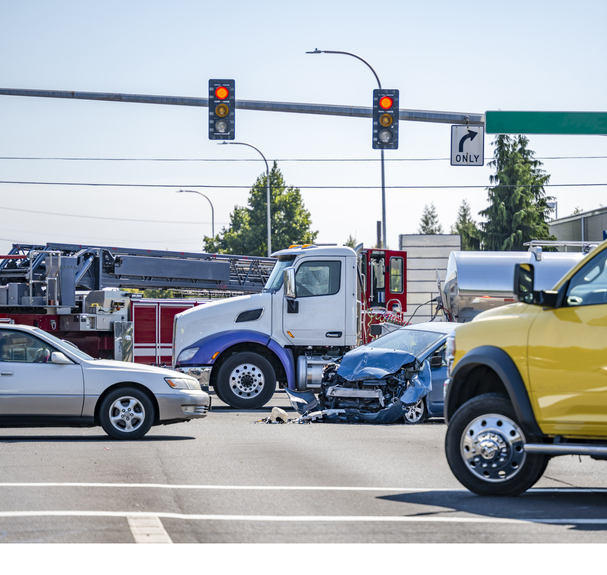semi-truck sits next to crashed car in the middle of an intersection - Kansas City truck accident attorneys